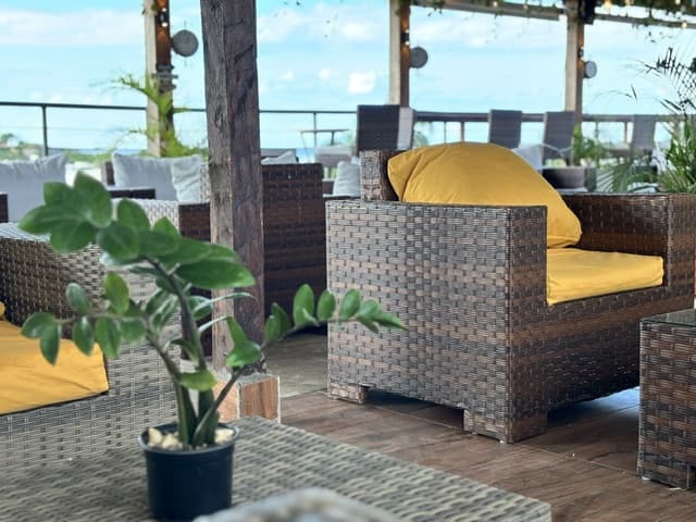 Sillón de mimbre con cojines amarillos en la terraza del hotel