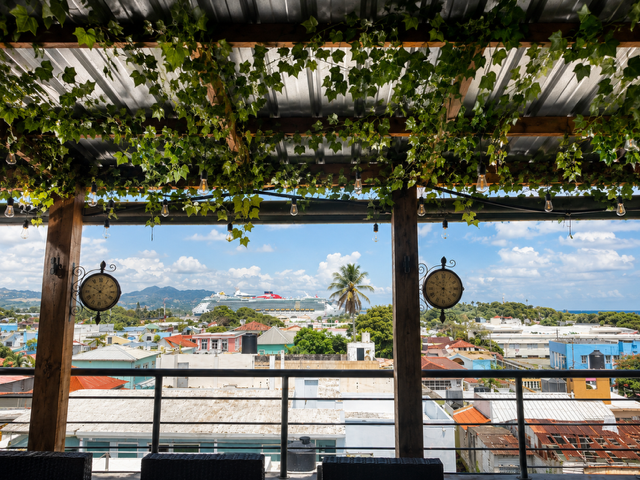 Relojes decorativos en la terraza, con vista a la ciudad y un crucero de fondo