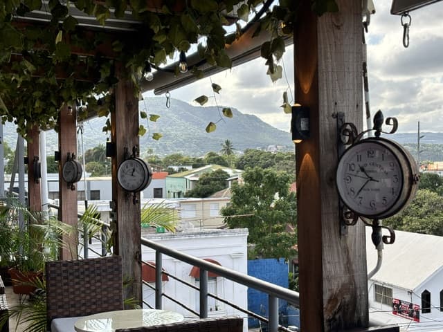 Detalle de relojes antiguos decorativos en la terraza, con las montañas de Puerto Plata al fondo