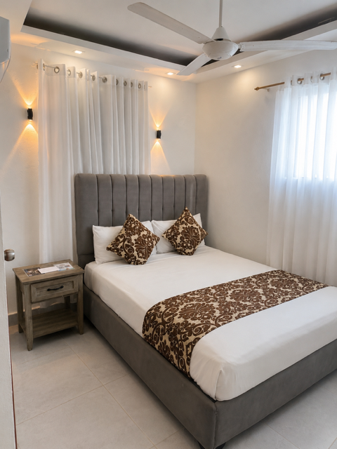 Double Room, cama full con cabecera gris acolchada y cortinas blancas